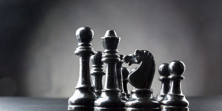 Set of black chess figures on the table over black